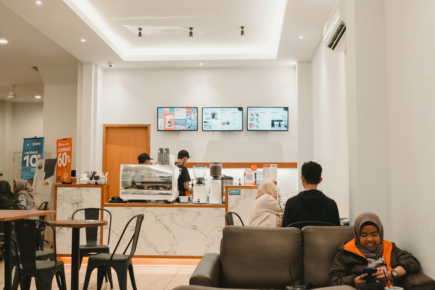 Baristas serve customers at a modern cafe counter.