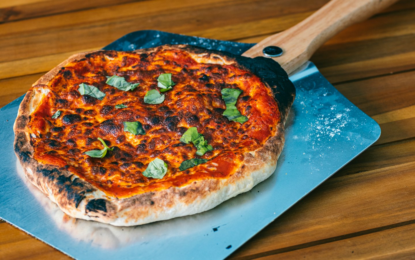 Freshly baked pizza on a metal pizza peel.