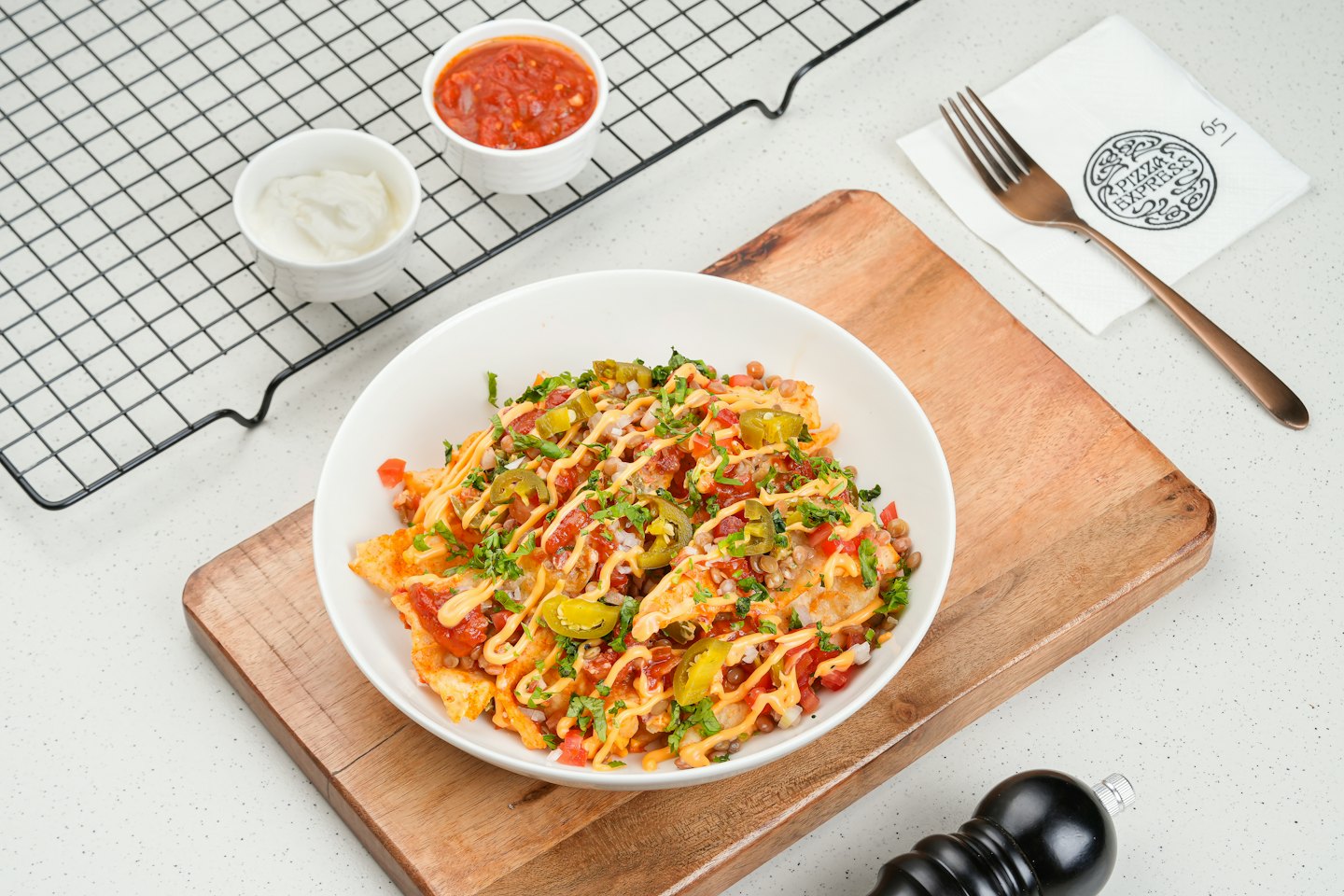 Loaded fries with cheese, tomatoes, and cilantro on a wooden board.