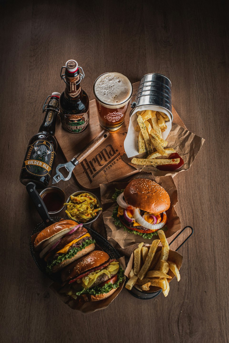 Gourmet cheeseburgers and fries spread out on a wooden table.