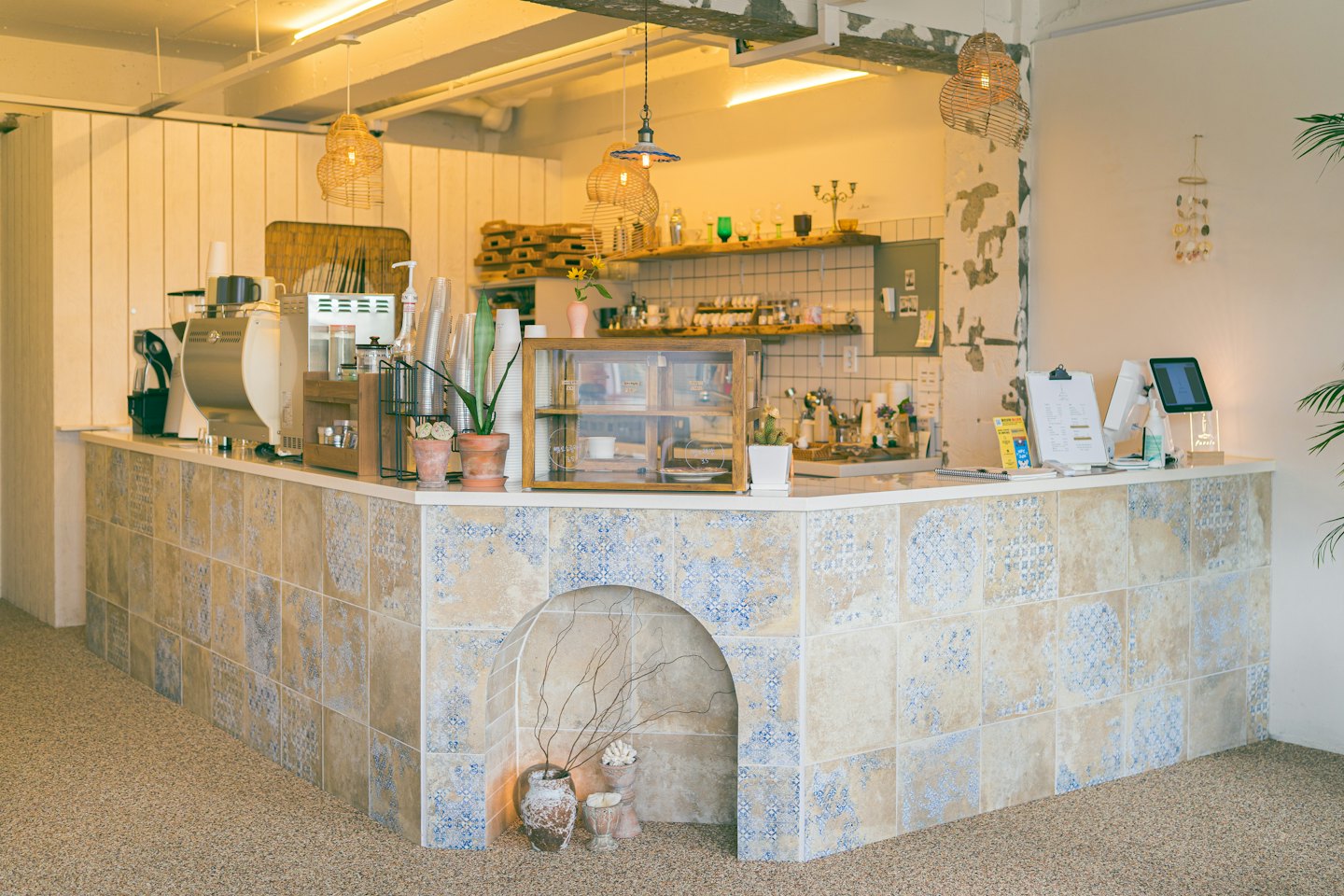 Tiled coffee shop counter with machines and glass display case.